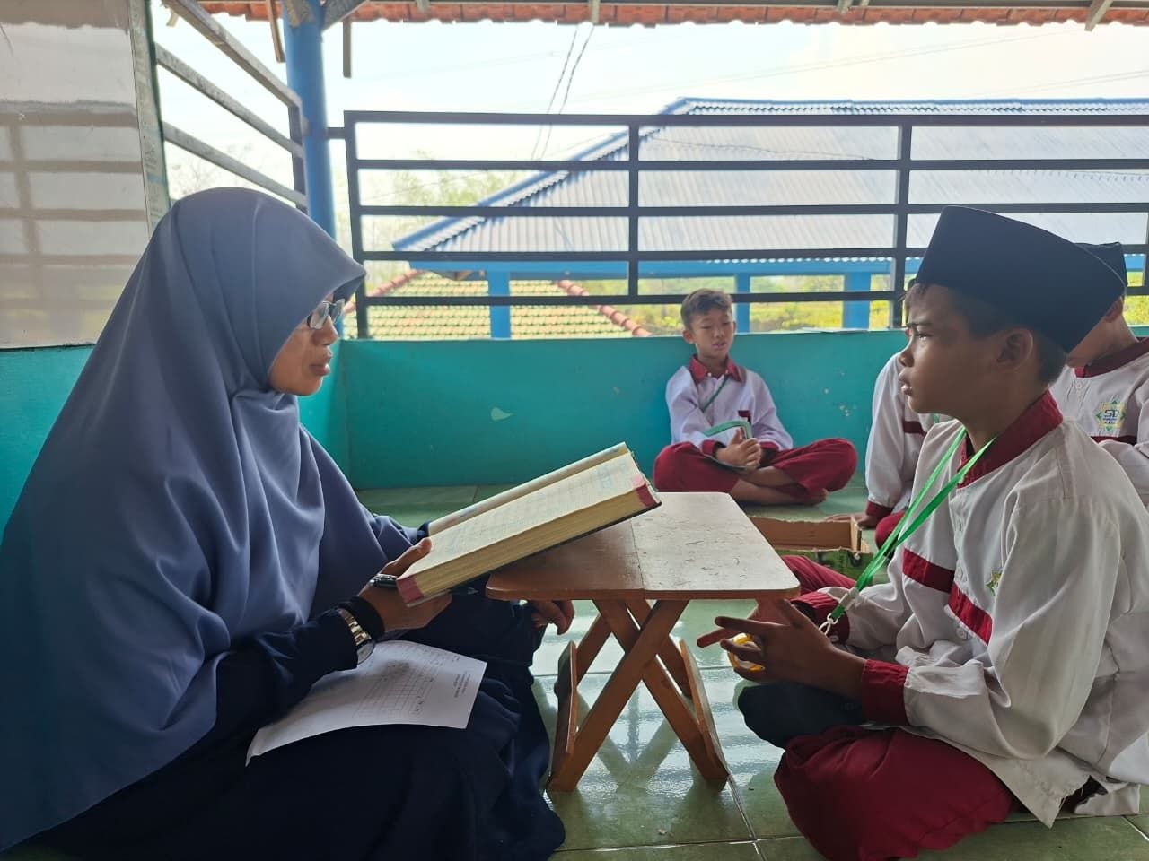 Ustadzah menyimak setoran hafalan Al-Quran santri cilik di beranda asri